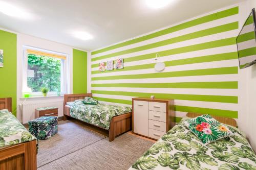 a bedroom with two beds and a striped wall at Pokoje Goscinne Oliwia & Laura II in Rumia
