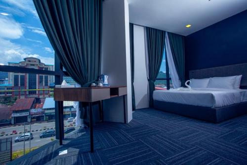 a bedroom with a bed and a desk and windows at We Hotel Langkawi in Kuah