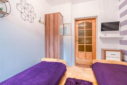 a bedroom with two purple beds and a door at Pokoje Goscinne Oliwia & Laura II in Rumia