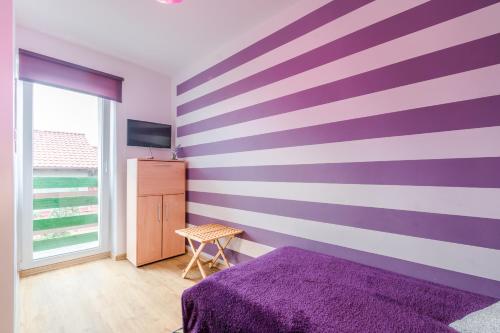 a bedroom with a purple and white striped wall at Pokoje Goscinne Oliwia & Laura II in Rumia