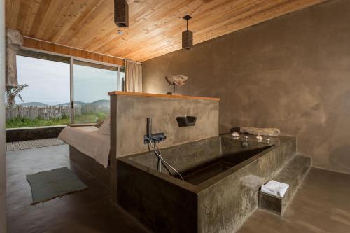 a large stone tub in a room with a bed at Santa Barbara Eco-Beach Resort in Ribeira Grande