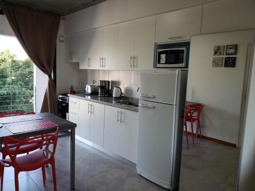 a kitchen with white cabinets and a table and a refrigerator at DEPARTAMENTO VERA MUJICA 1 cochera propia incluida in Rosario
