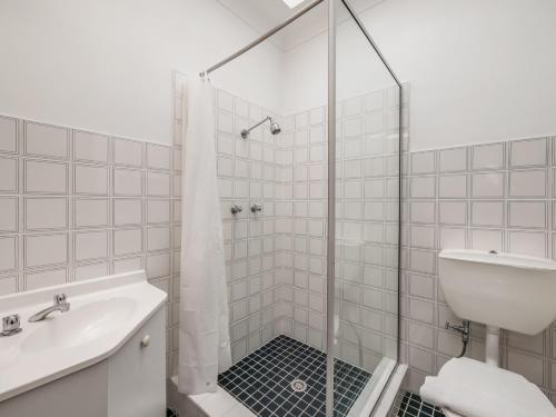 a white bathroom with a shower and a sink at Snowy Valley Jindabyne in Jindabyne