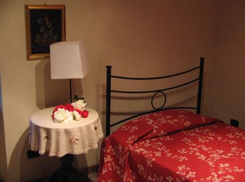 een slaapkamer met een bed en een tafel met bloemen erop bij La Miseria in Ovada