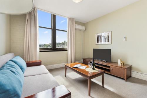 a living room with a couch and a tv at Launceston Central Apartment Hotel Official in Launceston