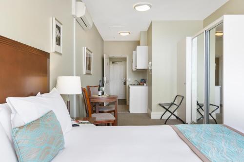 Launceston Central Apartment Hotel Official في لونسيستون: غرفة نوم مع سرير وغرفة معيشة