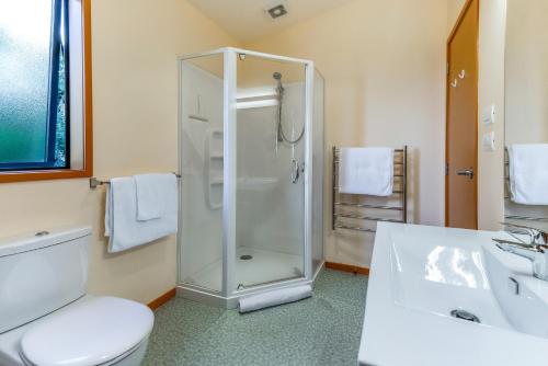 a bathroom with a shower and a toilet and a sink at Moeraki with private walkway to Onetangi Beach by Waiheke Unlimited in Onetangi