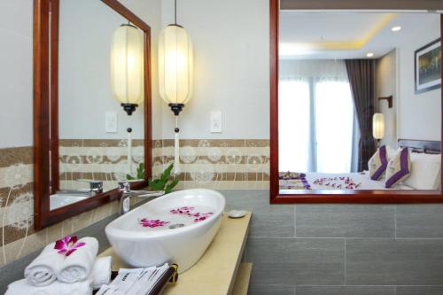 a bathroom with a sink and a large mirror at Uptown Hoi An Hotel & Spa in Hoi An