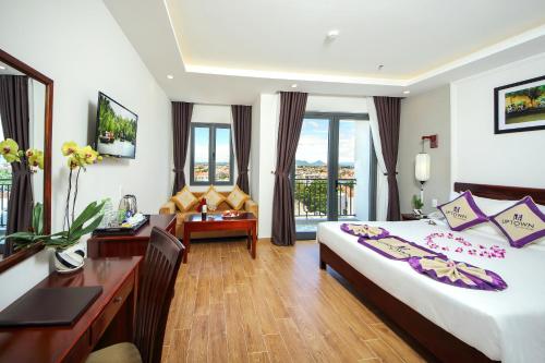 a hotel room with a bedroom with a desk and a bed at Uptown Hoi An Hotel & Spa in Hoi An