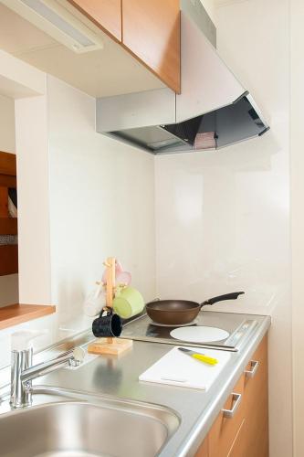 a kitchen with a sink and a frying pan on a stove at Stay Asahikawa Koto in Asahikawa