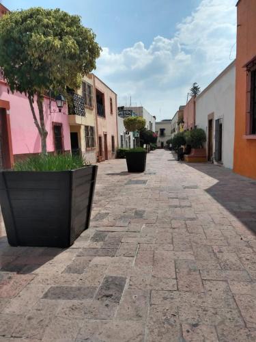 an empty street in a town with trees and buildings at Hotel Cuauhtemoc in Querétaro