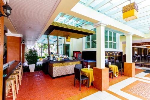 a restaurant with a bar with yellow tables and chairs at Krabi Front Bay Resort in Krabi