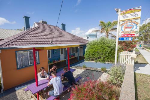 a group of people sitting on a swing outside a house at Dolphin Retreat Bunbury YHA in Bunbury