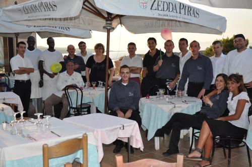 a group of people posing for a picture in front of tables at Hotel Le Dune in Porto Pollo