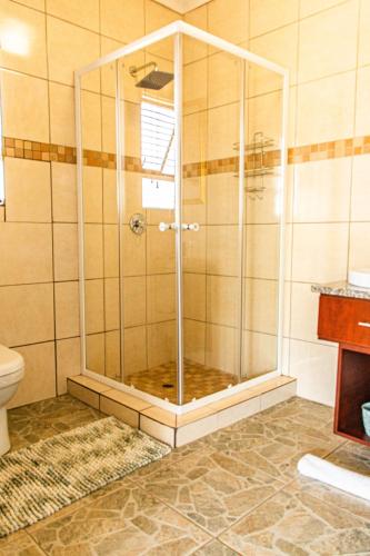 a shower with a glass door in a bathroom at Tinyiko Kruger Lodge in Marloth Park