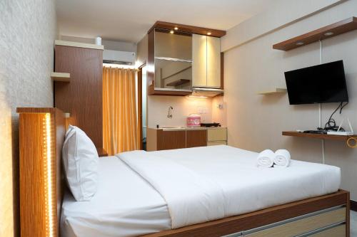 a bedroom with a white bed and a television at Modern Studio Apartment at Cinere Resort By Travelio in Depok