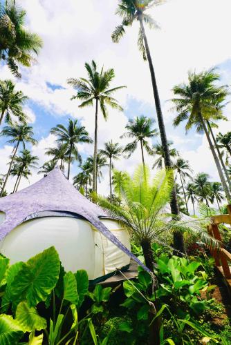 a boat sitting in the bushes with palm trees at Nacpan Beach Glamping Managed by H Hospitality Group in El Nido