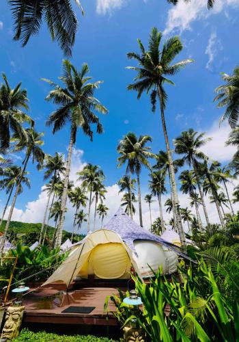 a tent in the grass with palm trees at Nacpan Beach Glamping Managed by H Hospitality Group in El Nido