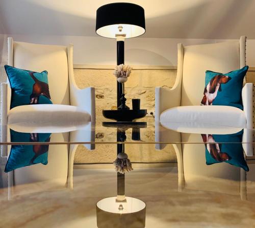 two chairs and a glass table with a lamp at Moulin Royale in Saint-Etienne-Roilaye