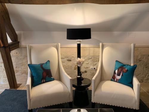 two white chairs with a lamp in a room at Moulin Royale in Saint-Etienne-Roilaye