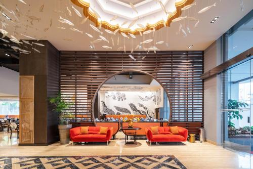 eine Lobby mit zwei orangenen Stühlen und einem Tisch in der Unterkunft Luminor Hotel Kota Jakarta By WH in Jakarta