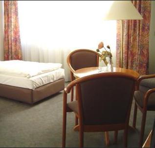 a bedroom with a bed and a table and a chair at Hotel Stiftswingert in Mainz