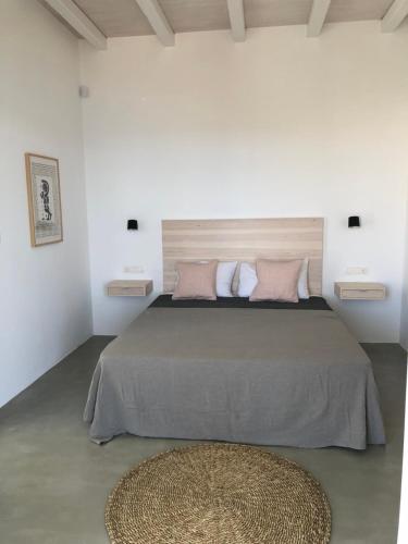 a white bedroom with a large bed with pink pillows at Theros apartments 2 in Mylopotas