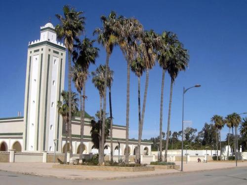 a building with a clock tower in front of palm trees at Perle d'Azur F3 in Saidia 