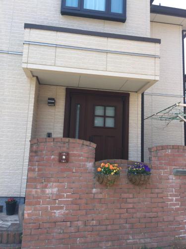 a house with a brick wall with two flower boxes at 花沢民宿 in Odawara