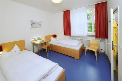 a hotel room with two beds and a desk at Bildungshaus Neckarelz in Mosbach