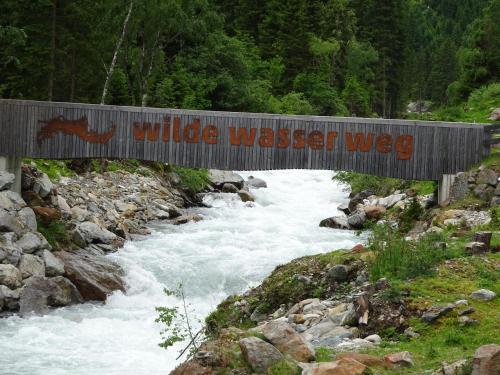 a bridge over a river with a sign that reads wildlife washer way at Chalet Stubai inklusive Stubai Super Card in Fulpmes