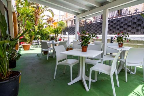 a patio with white tables and chairs and plants at Kunesias B&B in Cinisi