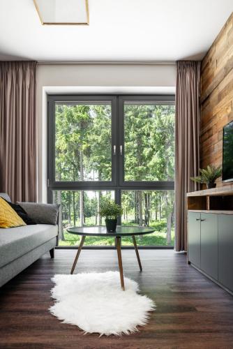 a living room with a table and a large window at Hotel Královka in Bedřichov