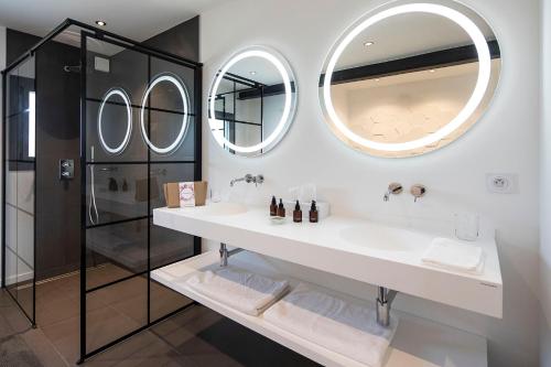 une salle de bain avec un lavabo et deux miroirs dans l'établissement Maison Galatéa, à Noves