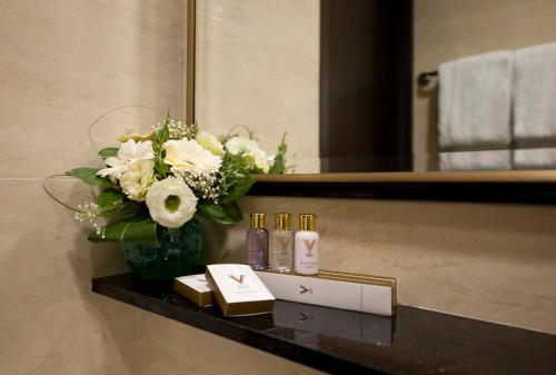 V Hotel Lavender في سنغافورة: إناء من الزهور على رف في حمام