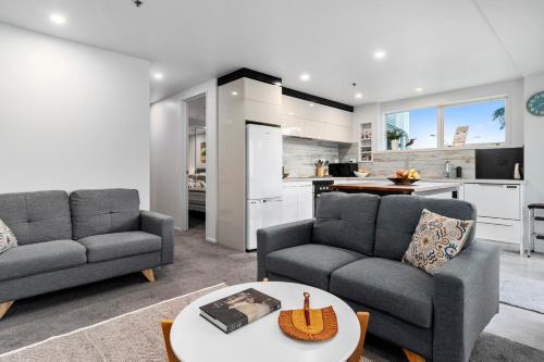 a living room with two couches and a kitchen at Kingsview CBD Tauranga in Tauranga