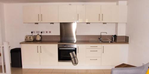 a kitchen with white cabinets and a sink at Impressive Urban Townhouse - Leeds City Centre in Leeds