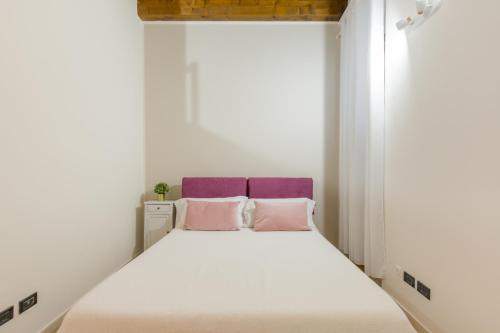a bedroom with a white bed with pink pillows at Maison Porta Leoni in Verona