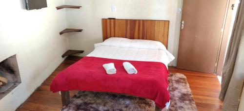 1 dormitorio con 1 cama con manta roja en Pousada Duas Quedas, en Campos do Jordão