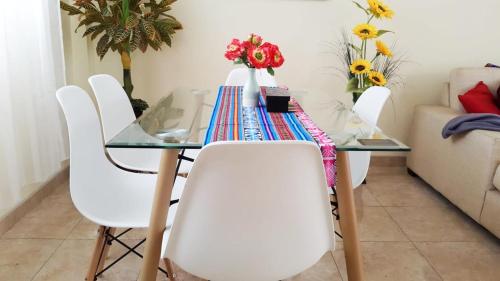 una mesa de cristal con sillas blancas y flores. en Departamento de estreno Pueblo Libre, en Lima