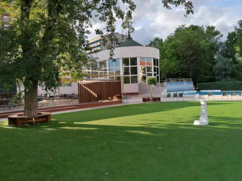 a building with a green lawn in front of a building at Hotel Barátság in Hajdúszoboszló
