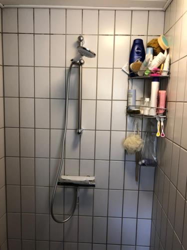 a white tiled bathroom with a shower on a wall at Jette’s værelsesudlejning in Rudkøbing