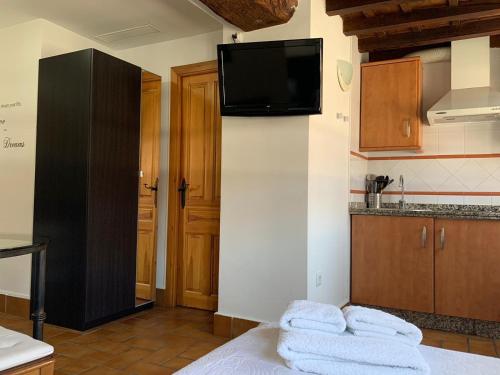 a kitchen with a tv on a wall with towels on a bed at Apartamento Corredera in Córdoba