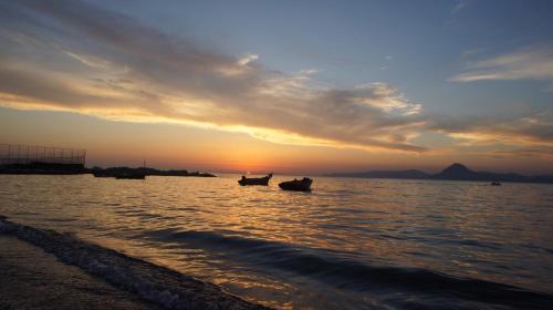 two boats in the water at sunset on the beach at Patras Cozy Lodge in Patra