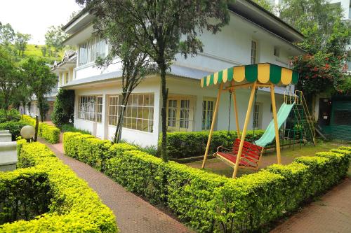 a playground in front of a house with a swing at Eastend Munnar in Munnar