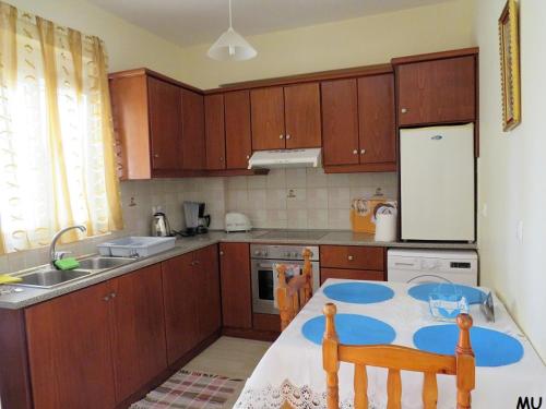 a kitchen with wooden cabinets and a table with chairs at Holiday Dream Thalia Apartment in Mastichari
