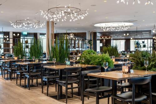 un restaurante con mesas, sillas y lámparas de araña en Quality Airport Hotel Gardermoen, en Gardermoen