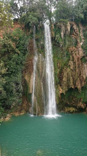 a waterfall over a pool of water in front of a mountain at Villa COLIBRI in Lorgues