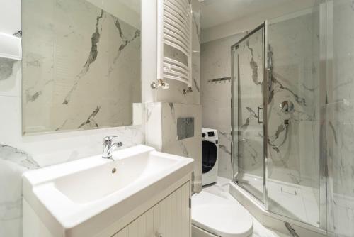 uma casa de banho com um lavatório, um chuveiro e um WC. em Riviera Rooms em Sopot