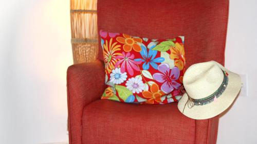 a hat sitting on a red chair with a flower pillow at Mirmar Apartments in Cumbuco
